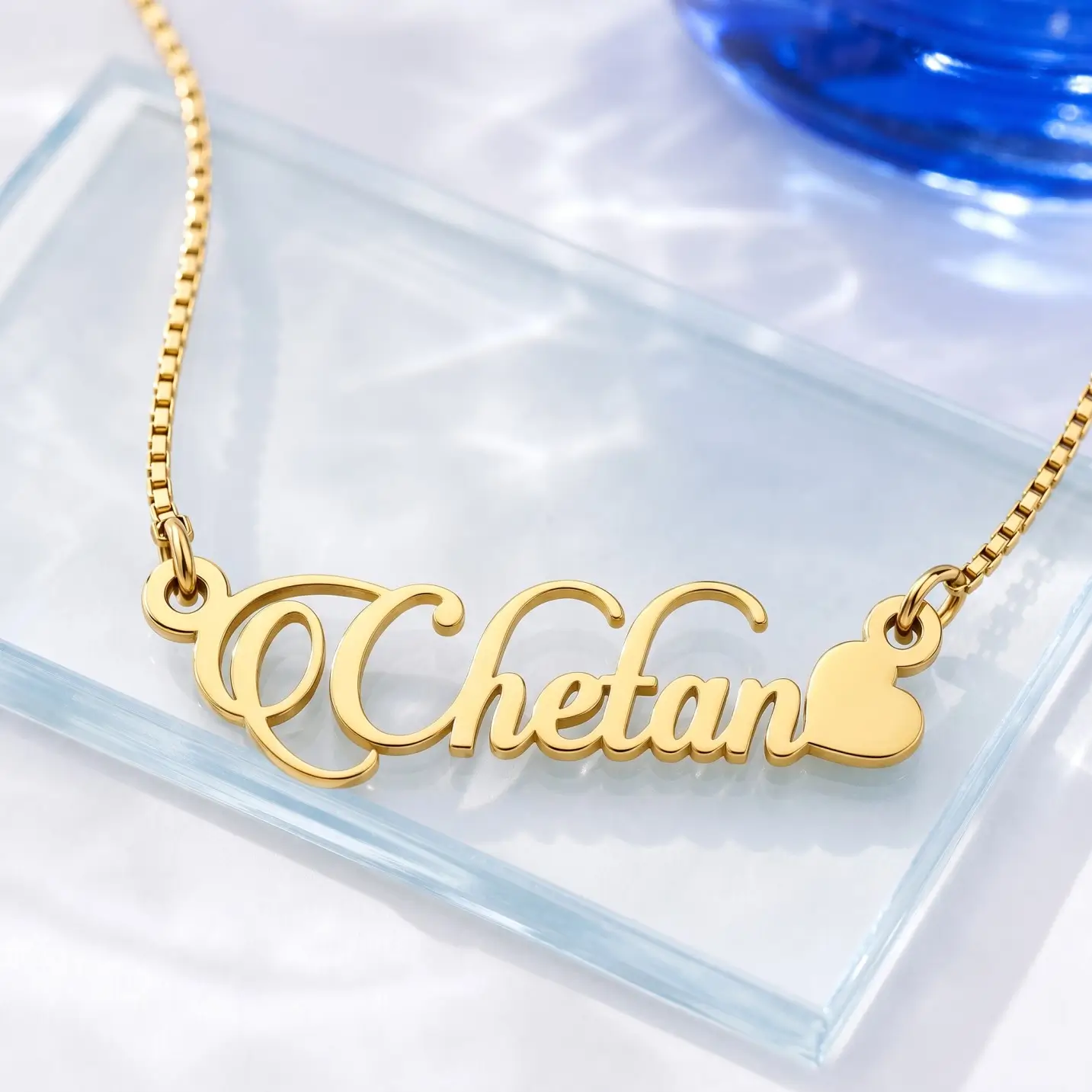 Stylish Heart Name Necklace - Glass Display Gold-tone decorative script name necklace with a heart on a clear glass display