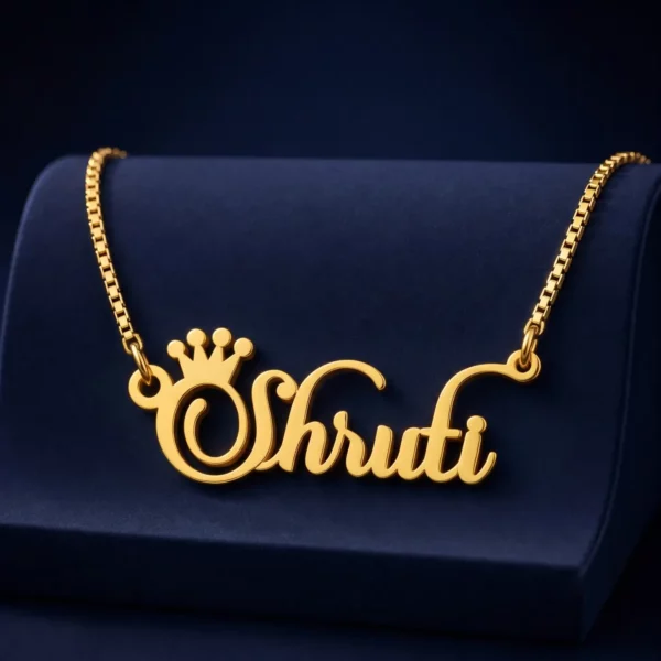 Gold-tone crown name necklace on a navy velvet display