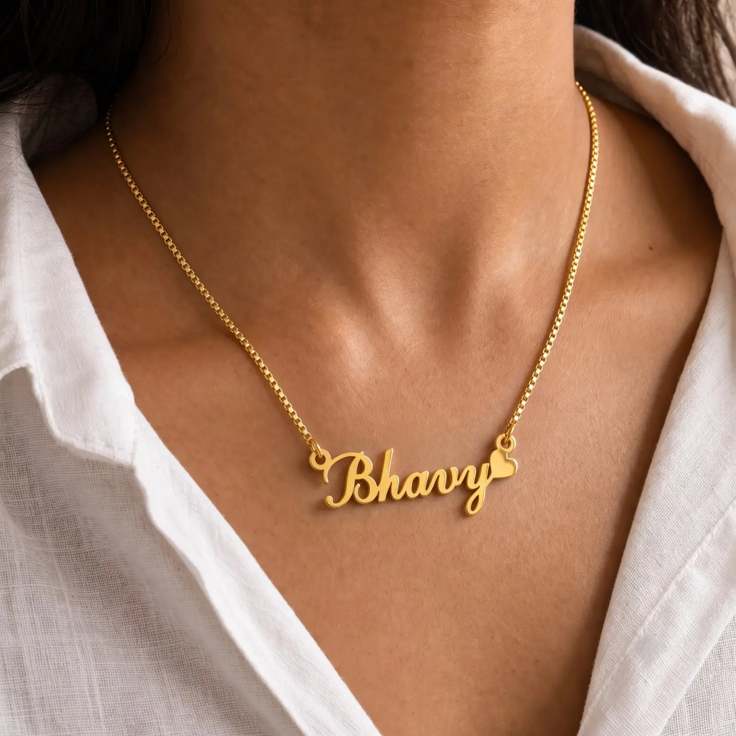 Curved Heart Name Necklace - Worn View Gold-tone curved script name necklace with a heart worn with a white blouse