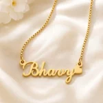 Gold-tone curved script name necklace with a heart on ivory satin