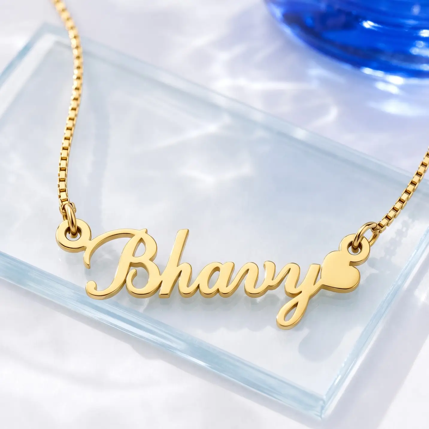 Curved Heart Name Necklace - Glass Display Gold-tone curved script name necklace with a heart on a clear glass display