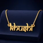 Gold-tone Indian style name necklace on a navy velvet display