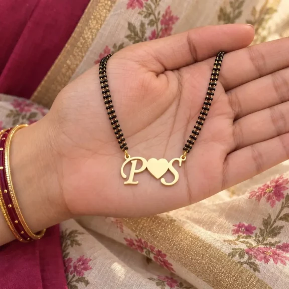 Heart Initials Couple Necklace with a black-beaded chain held in a hand