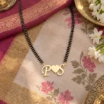 Heart Initials Couple Necklace with a black-beaded chain on floral fabric