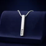 Silver-tone personalized 3D bar pendant with an engraved name on a navy velvet display