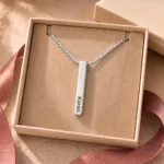 Silver-tone personalized 3D bar pendant with an engraved name displayed in an open beige jewellery box
