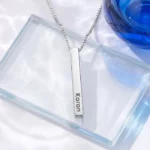 Silver-tone personalized 3D bar pendant with an engraved name on a clear glass display