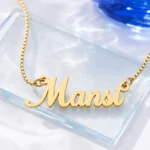 Gold-tone simple script name necklace on a clear glass display