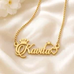 Gold-tone name necklace with crown, star and heart accents on ivory satin