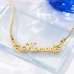 Gold-tone angel wings name necklace on a clear glass display