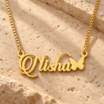 Gold Nisha butterfly name necklace on warm textured stone