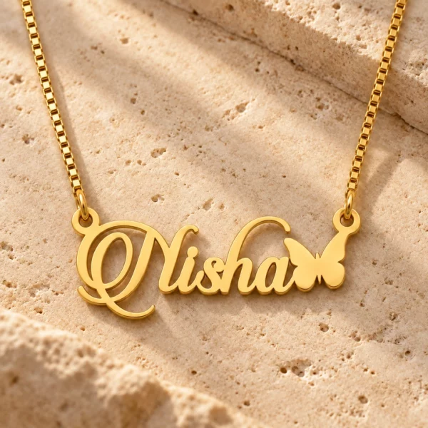 Gold Nisha butterfly name necklace on warm textured stone