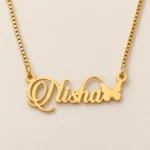 Gold Nisha ornate script name pendant with butterfly and golden box chain, clean ivory product view