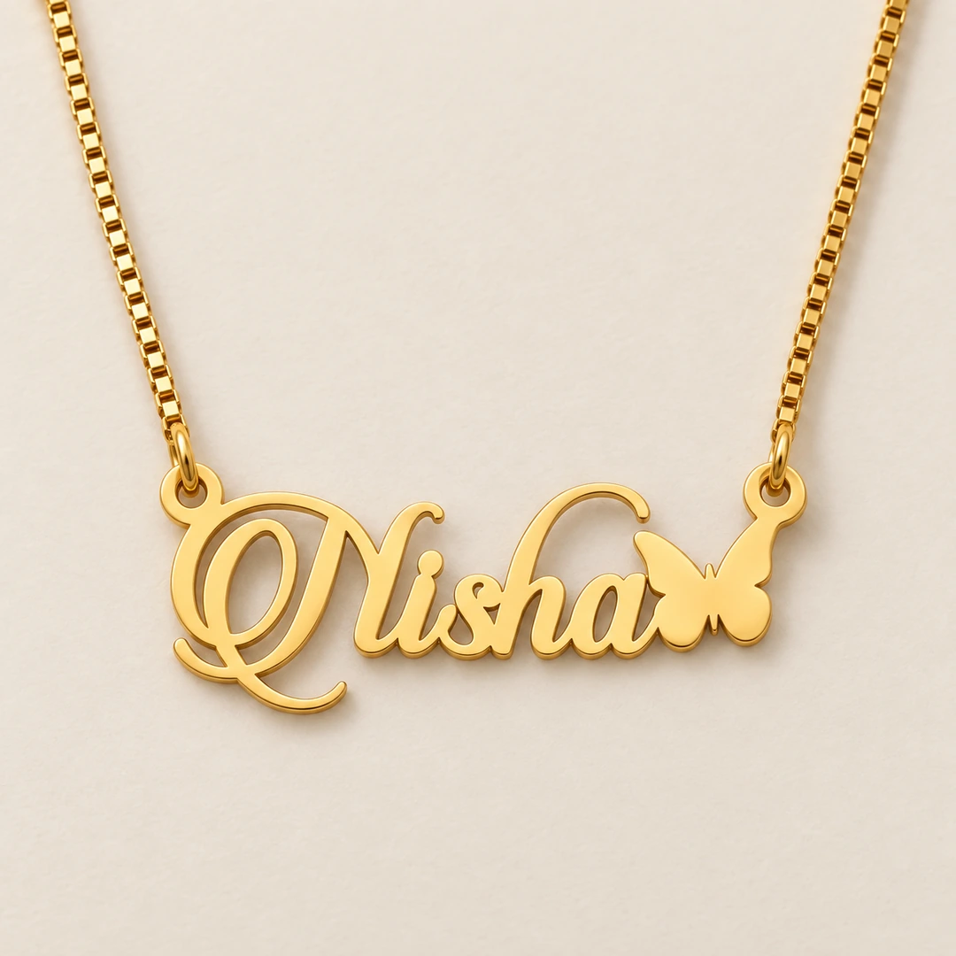 Butterfly Style Name Necklace - Reshoot 1 Gold Nisha ornate script name pendant with butterfly and golden box chain, clean ivory product view