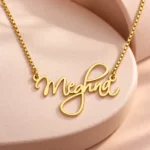 Cursive Curved Name Necklace with original gold box chain on ceramic detail background