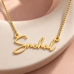 Gold Snehal signature name pendant and box chain on curved ceramic