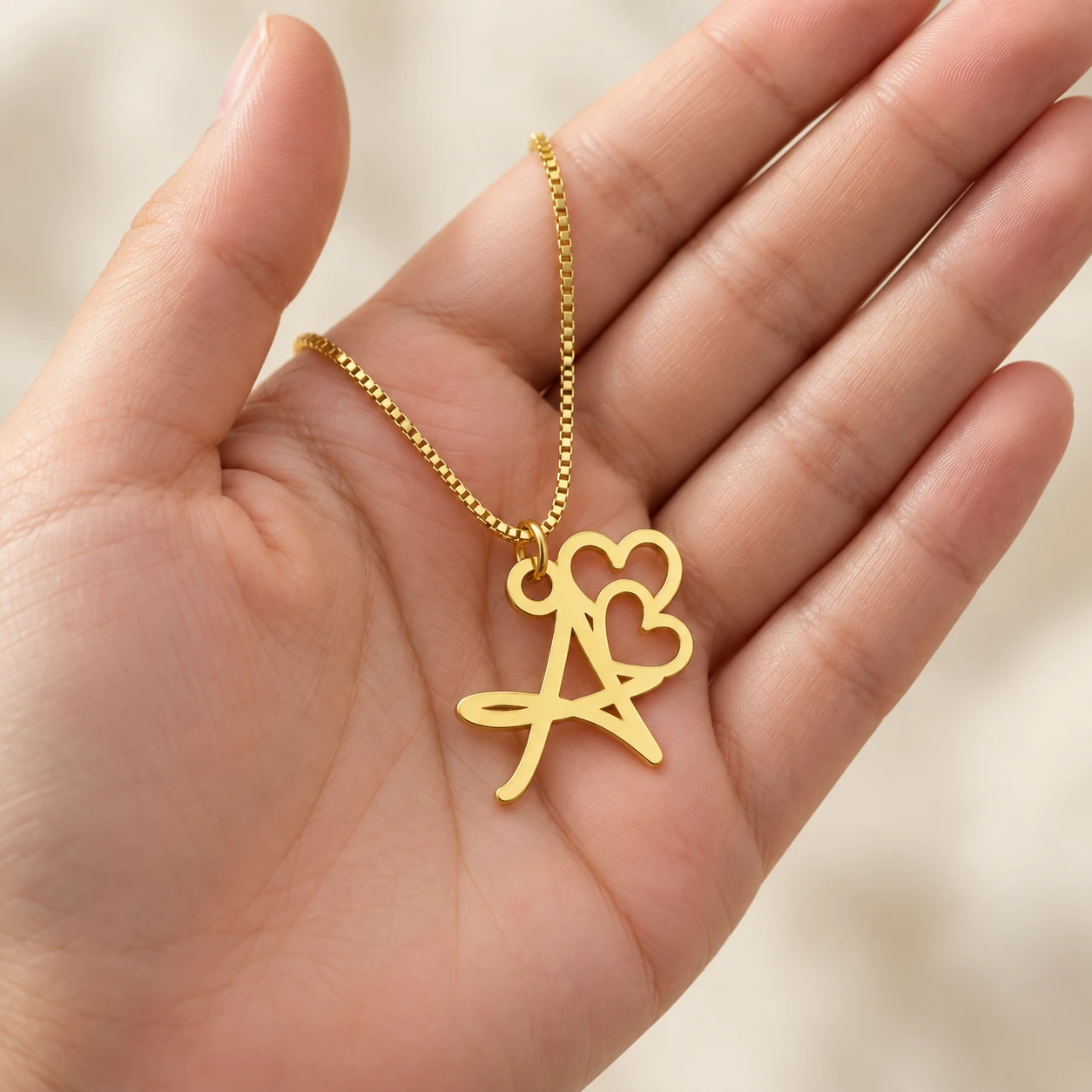 Double Heart Letter Pendant - With a chain held in a hand Double Heart Letter Pendant with a chain held in a hand