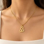 Gold B letter pendant with integrated heart cutout and fine box chain, model worn