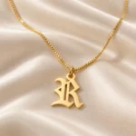 Old English Letter Pendant with a chain on cream fabric