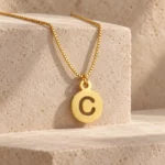 Round Letter Pendant with a chain on a stone display