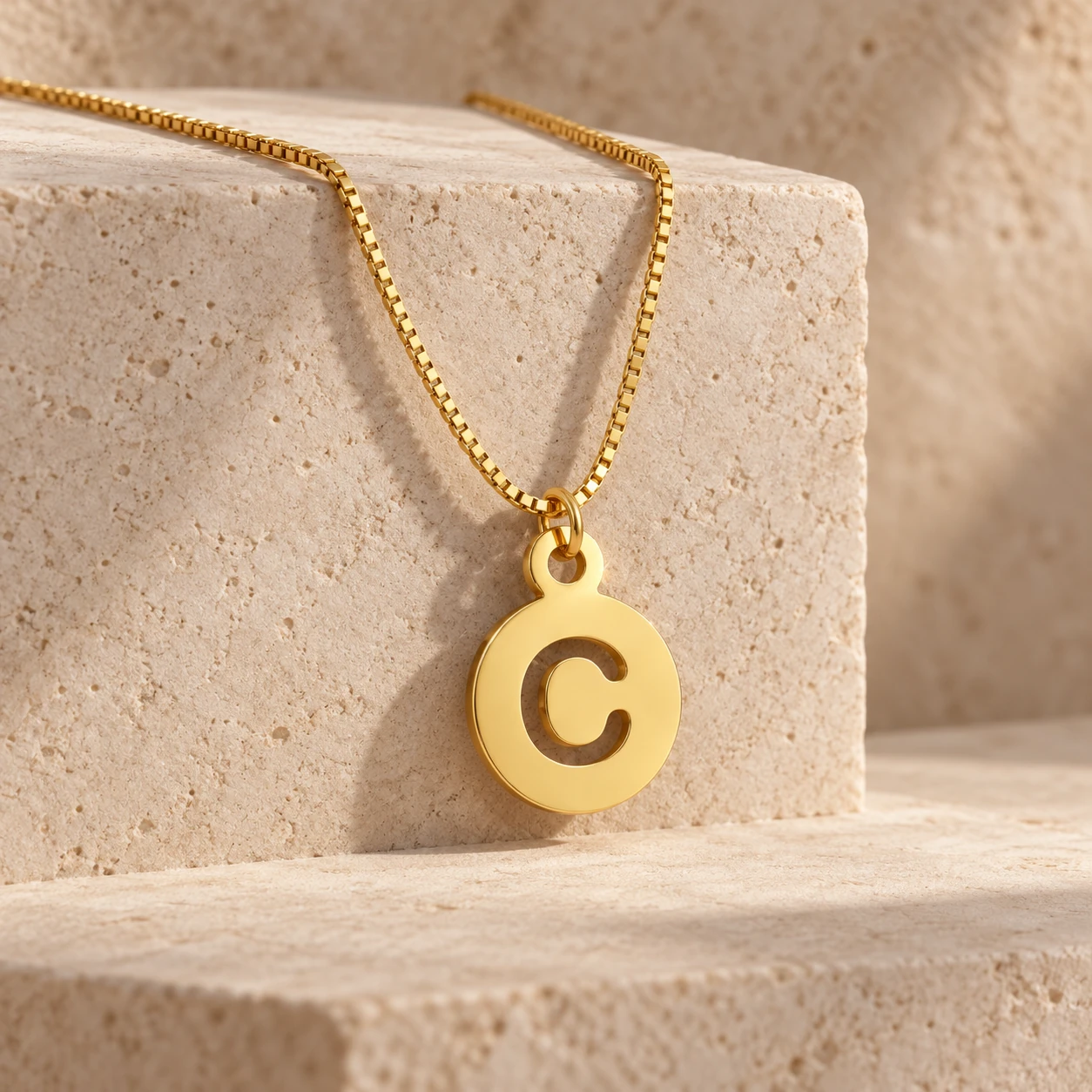 Round Letter Pendant - With a chain on a stone display Round Letter Pendant with a chain on a stone display
