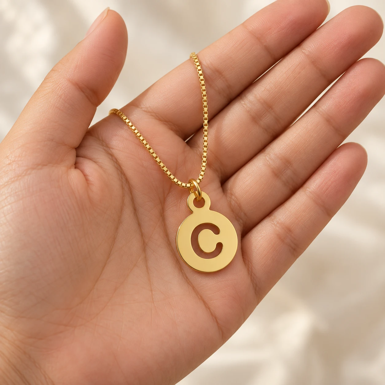 Round Letter Pendant - With a chain held in a hand Round Letter Pendant with a chain held in a hand