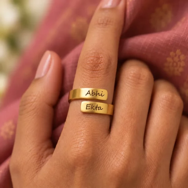 Personalized Engraved Couple Name Ring worn on a hand against rose-coloured fabric