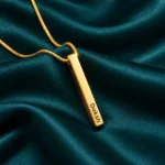 Gold plated 3D bar pendant with Daksh engraving and gold box chain, teal satin