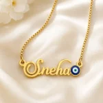 Gold-tone name necklace with a blue evil eye accent on ivory satin