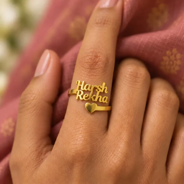Forever Heart Couple Name Ring worn on a hand against rose-coloured fabric