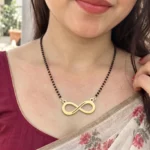 Gold-tone classic infinity pendant on a black-bead chain worn with a floral sari