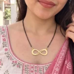 Gold-tone classic infinity pendant on a black-bead chain worn with a pink and white outfit