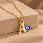 Blue Evil Eye Letter Pendant with a chain on a stone display