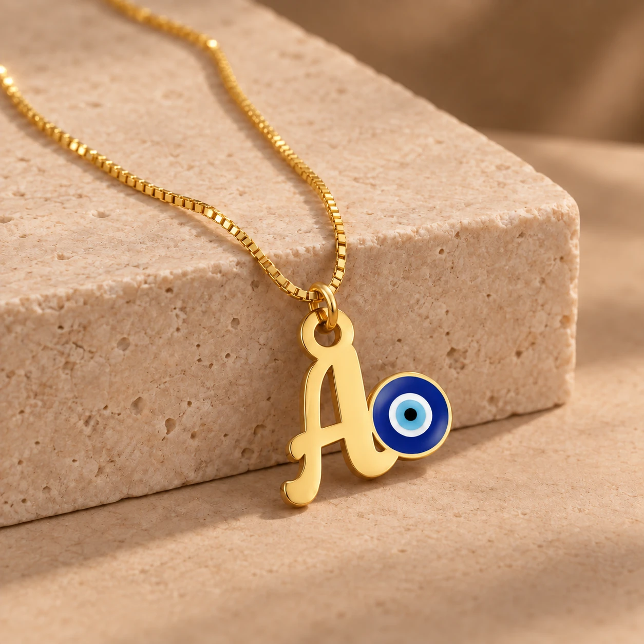 Blue Evil Eye Letter Pendant - With a chain on a stone display Blue Evil Eye Letter Pendant with a chain on a stone display