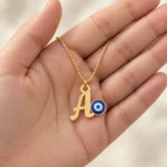 Blue Evil Eye Letter Pendant with a chain held in a hand