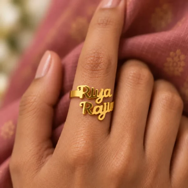 Forever Us Couple Name Ring worn on a hand against rose-coloured fabric