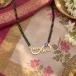 Blue Evil Eye Infinity Couple Name Necklace with a black-beaded chain on floral fabric