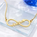 Gold-tone infinity outline name necklace on a clear glass display
