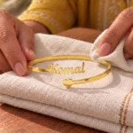 Personalized Heart Name Bracelet in a golden finish, displayed on folded cream fabric