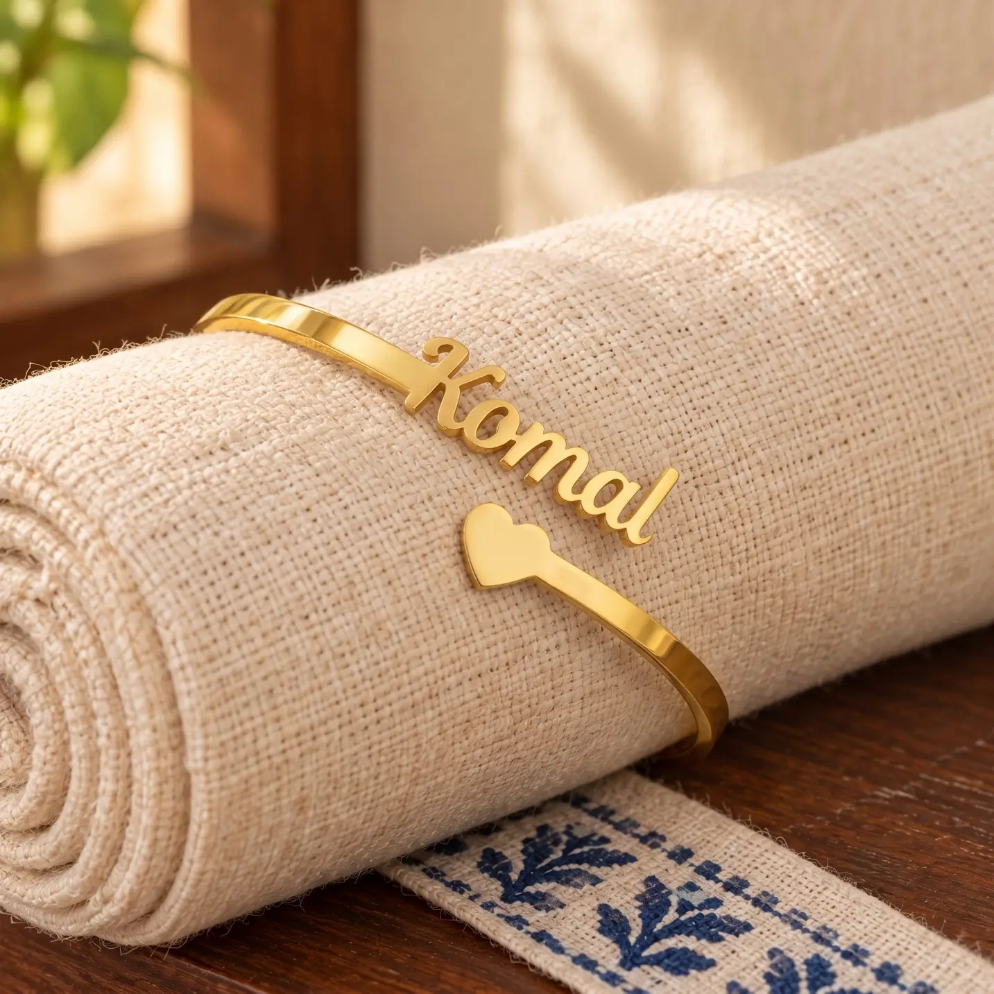 Personalized Heart Name Bracelet - Rolled Fabric Display Personalized Heart Name Bracelet in a golden finish, displayed on rolled cream fabric