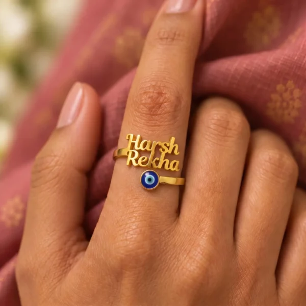 Personalized Evil Eye Couple Name Ring worn on a hand against rose-coloured fabric