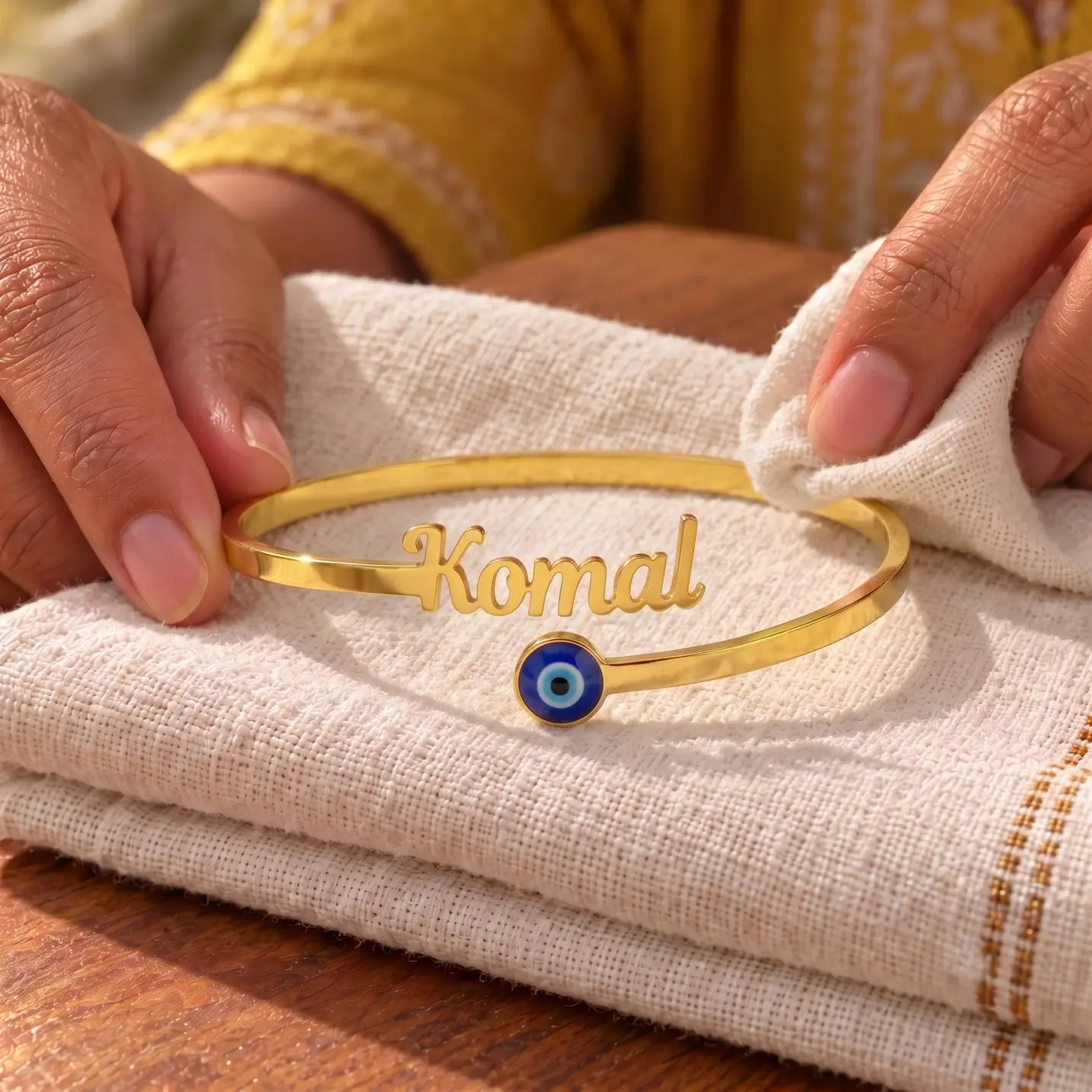 Personalized Evil Eye Name Bracelet - Folded Fabric Display Personalized Evil Eye Name Bracelet in a golden finish, displayed on folded cream fabric