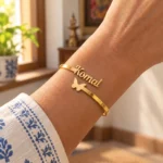Personalized Butterfly Name Bracelet in a golden finish, worn on a wrist beside a blue and white sleeve