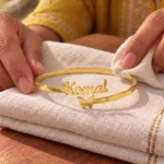 Personalized Butterfly Name Bracelet in a golden finish, displayed on folded cream fabric