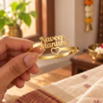 Open Heart Couple Name Bracelet in a golden finish, held in a hand showing the name design