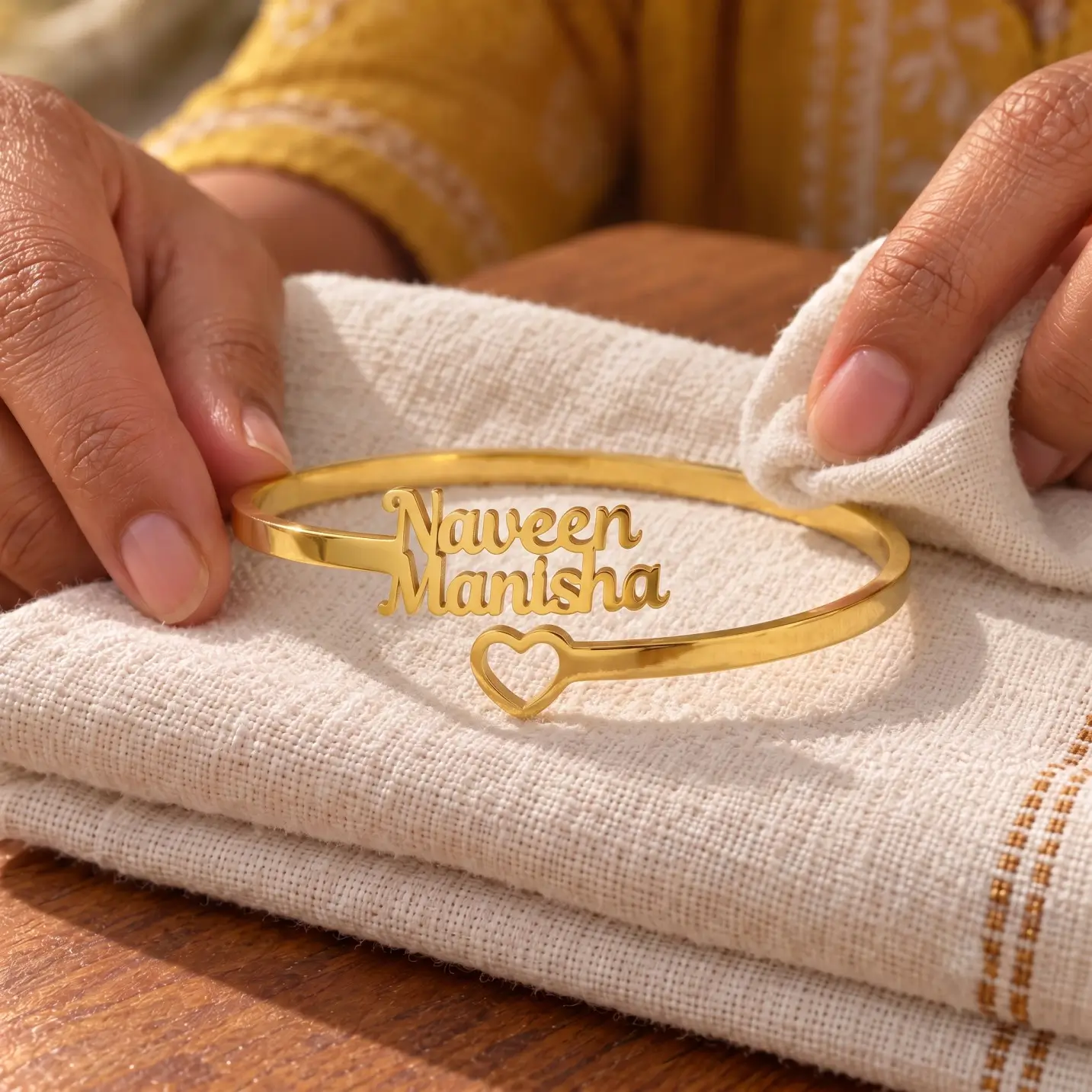Open Heart Couple Name Bracelet - Folded Fabric Display Open Heart Couple Name Bracelet in a golden finish, displayed on folded cream fabric