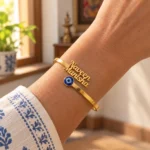 Personalized Evil Eye Couple Bracelet in a golden finish, worn on a wrist beside a blue and white sleeve