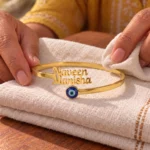 Personalized Evil Eye Couple Bracelet in a golden finish, displayed on folded cream fabric
