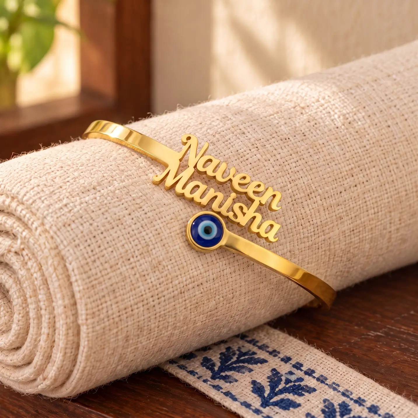 Personalized Evil Eye Couple Bracelet - Rolled Fabric Display Personalized Evil Eye Couple Bracelet in a golden finish, displayed on rolled cream fabric