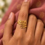 Two Hearts Personalized Love Ring worn on a hand against rose-coloured fabric